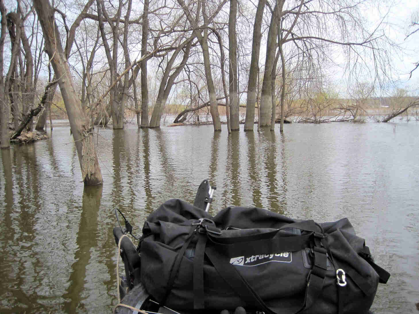 Front view of a of an inflatable raft with a gear pack on it, floating in a flooded area of the river bottoms